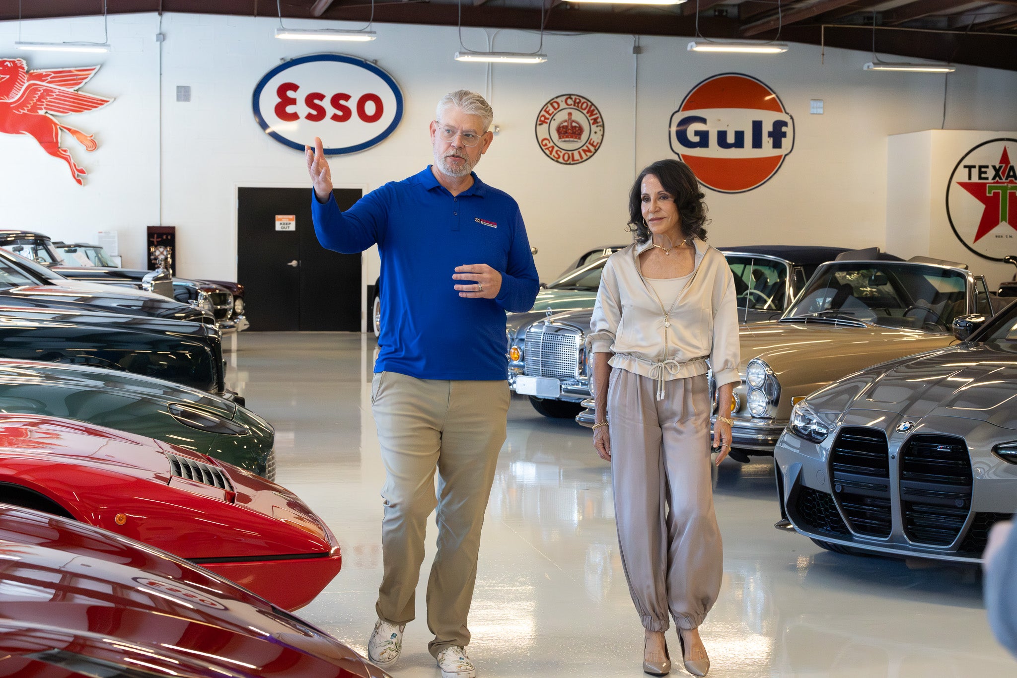 Man and woman walking through a classic car showroom